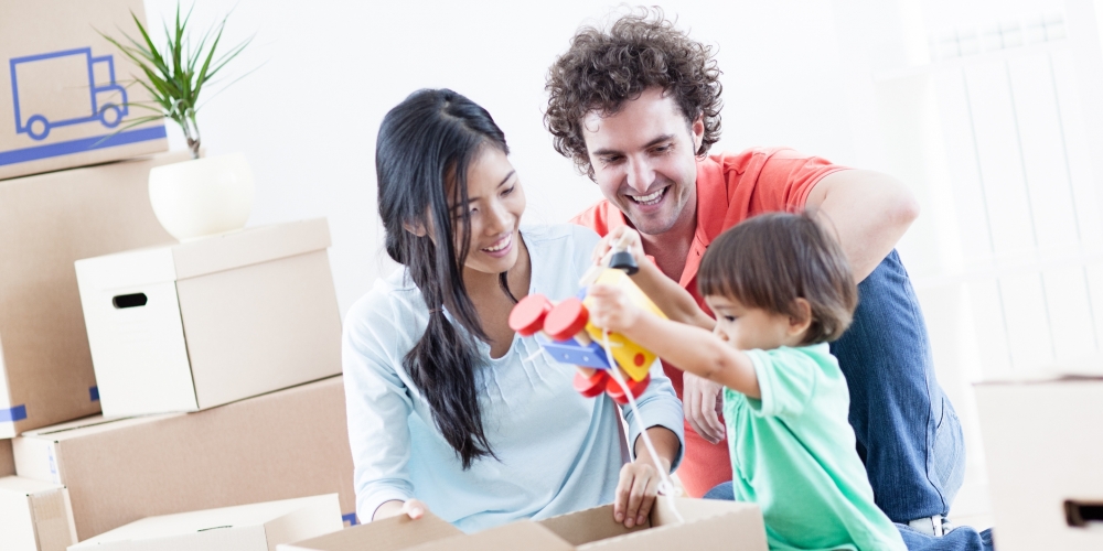 Happy couple and son unpacking boxes in their new home