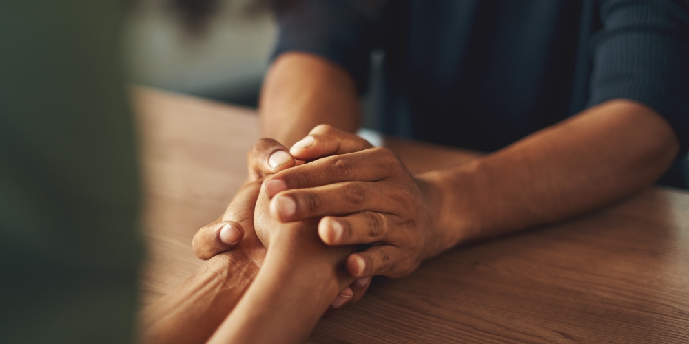 Two people are holding hands across a table. 