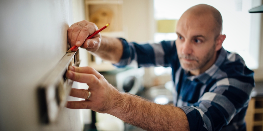 A man taking measurements for work in the kitchen