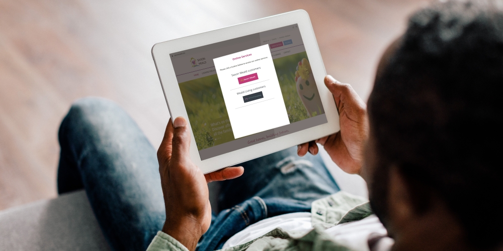 A man sitting on the sofa looking at the Saxon Weald website on an iPad