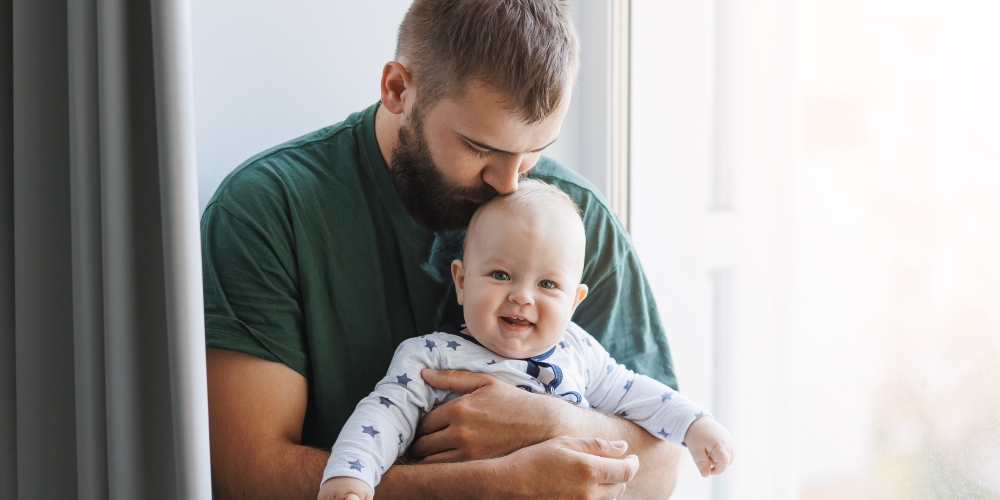 A father kissing his son on the forehead in a living room